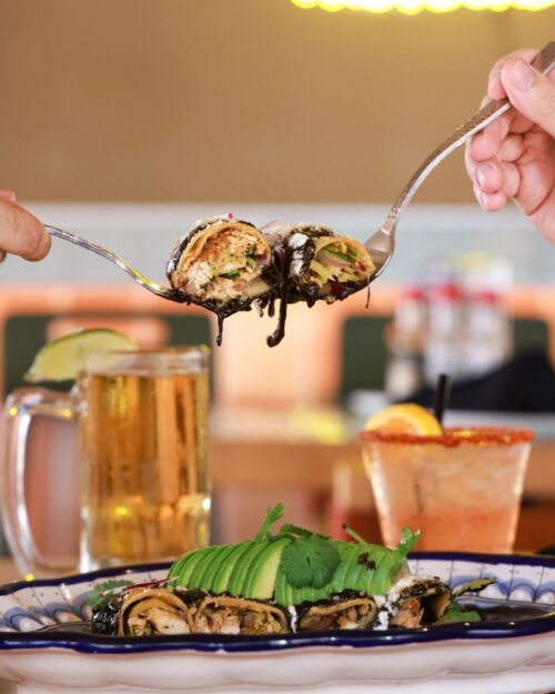 Puntamar food-beverage image A fork lifts a slice of stuffed enchilada drizzled with black sauce